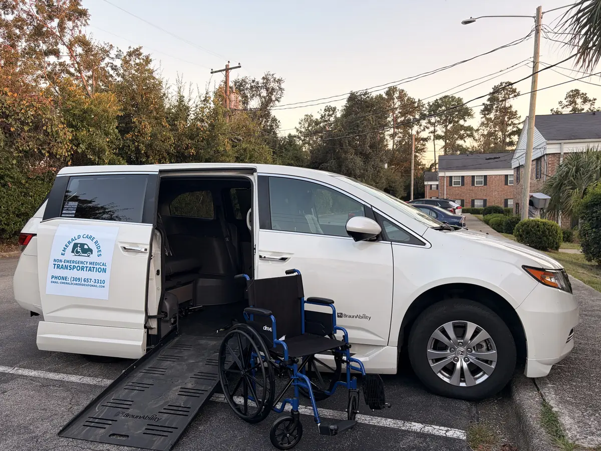The Emerald Care Rides van with its side ramp down and a wheelchair waiting at the foot of the ramp.