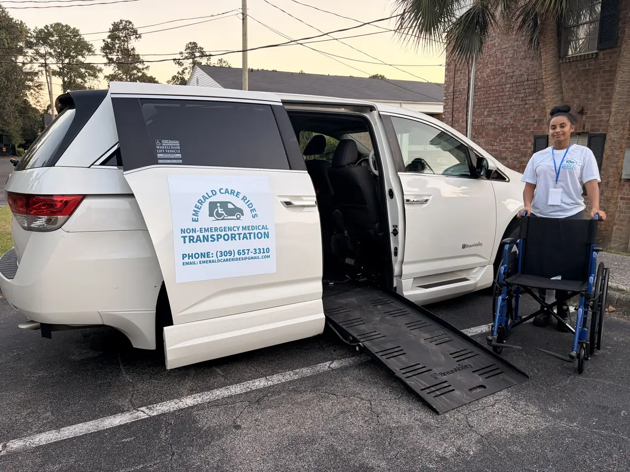 The Emerald Care Rides wheelchair van in Tallahassee, Florida, with its side ramp down, a wheelchair at the foot of the ramp and the driver standing beside it.